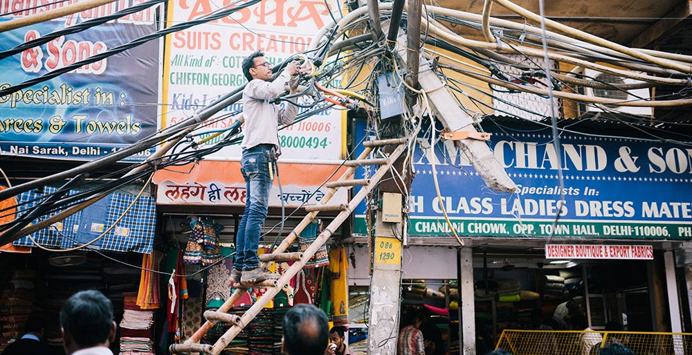A view of disordered power lines and an engineer at work, Delhi, India