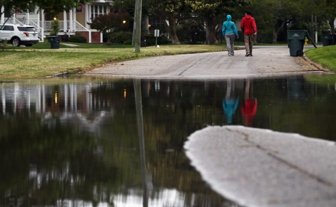 Two people walk on a flooded road