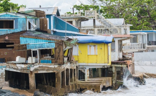 La fotografía muestra pequeños edificios de color turquesa, amarillo y blanco situados directamente sobre el agua en una costa en Rincón, Puerto Rico. Las aguas turbulentas son visibles. Rincón sufrió daños graves en el huracán María. Crédito: cestes001 (iStock / Getty Images Plus)