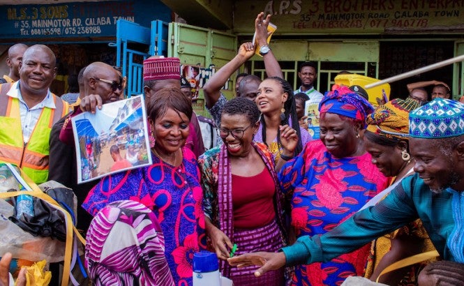 A group of people in brightly colored clothing smile at the camera outside.