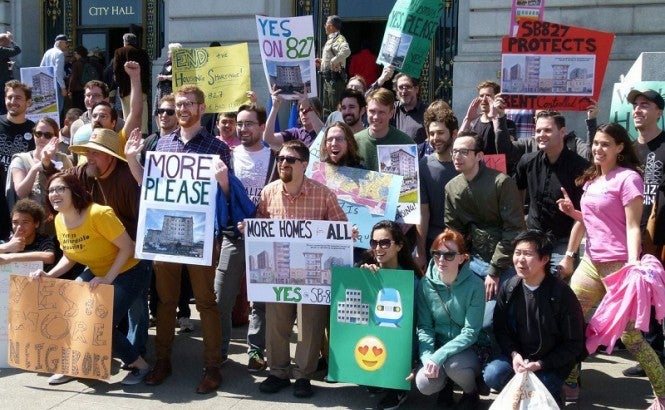 A group of YIMBY advocates pose for a picture with signs supporting California bill SB 827. 