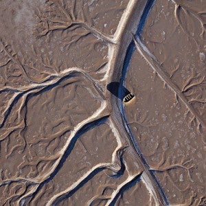 Aerial view of a fishing boat stranded on a brown and dried up Colorado River Delta.