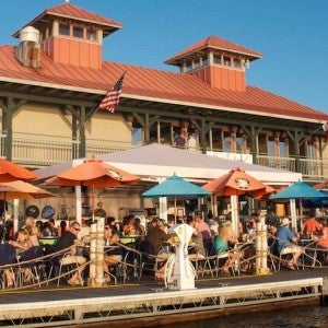 A waterfront restaurant with an outdoor patio full of diners.