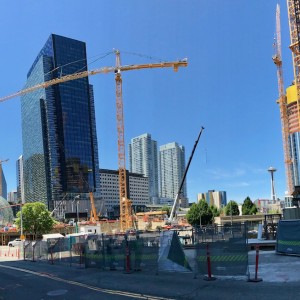 Two skyscrapers stands in front of a background of blue sky, with a crane in between.