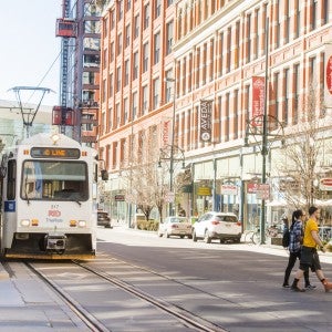 Downtown Denver, Colorado. Shown are a light rail train and a few pedestrians crossing the street.