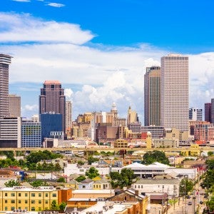 A cit skyline with large buildings in the background and smaller buildings and trees in the foreground. It's daytime.