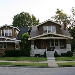 Two houses stand side by side with green lawns in the foreground.