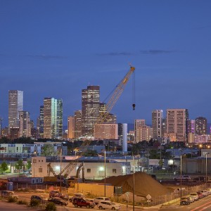 Nighttime with a train station in the foreground and tall buildings plus a crane in the background.