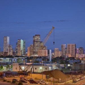 Nighttime with a train station in the foreground and tall buildings plus a crane in the background.