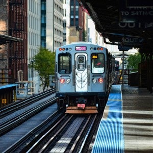 A train on a platform with buildings in the background.