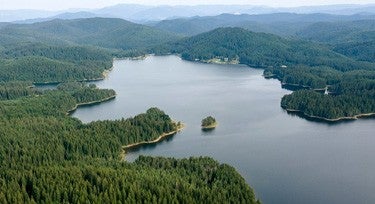 Body of water surrounded by green peninsula with mountains in the background