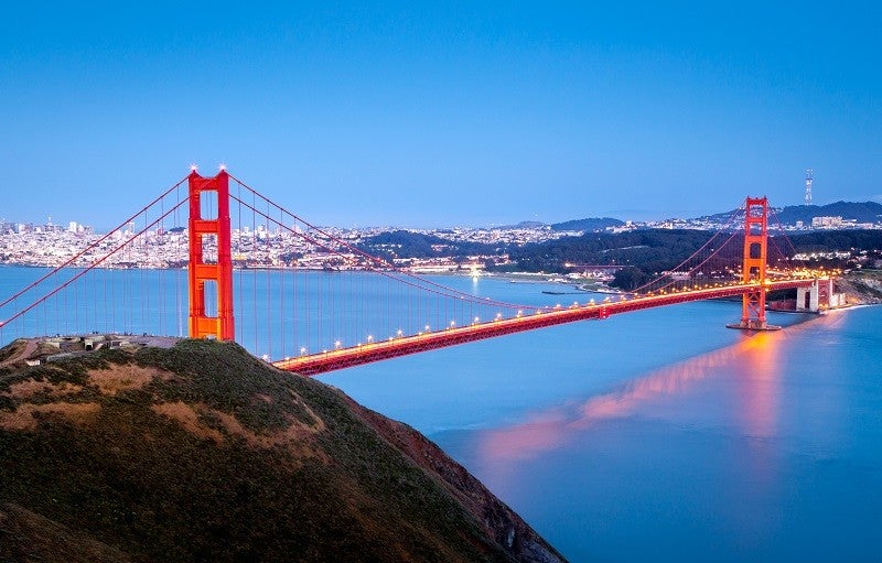 The Golden Gate Bridge at night. Credit: Getty Images Plus/Ultima_Gaina. This image shows the Golden Gate Bridge in the foreground and the city of San Francisco lit up at night in the background.