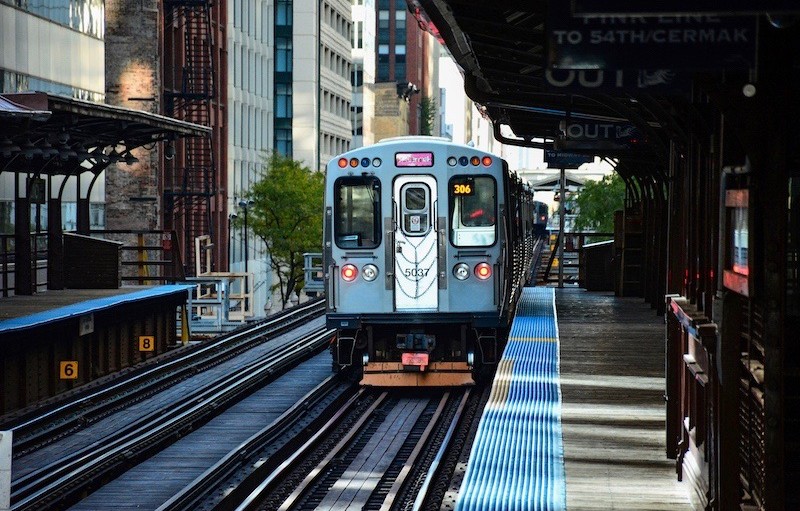 A train on a platform with buildings in the background.