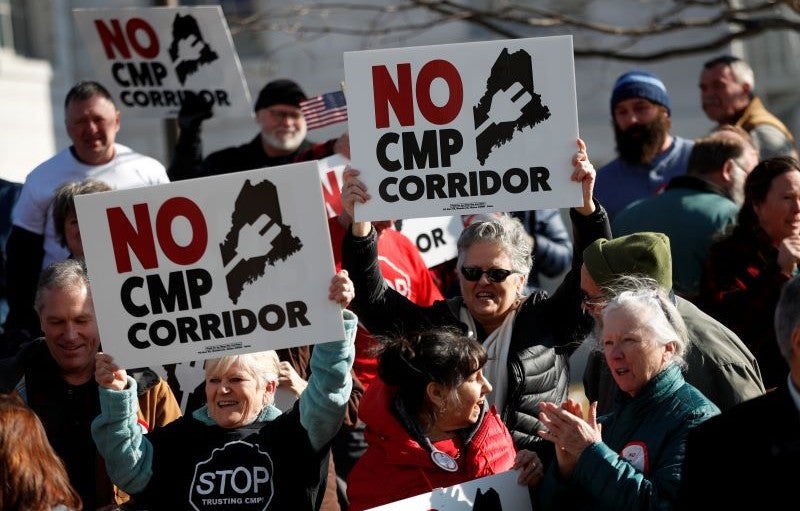 Credit: AP Photo/Robert F. Bukaty Protesters hold signs opposing a planned hydroelectric corridor in Maine