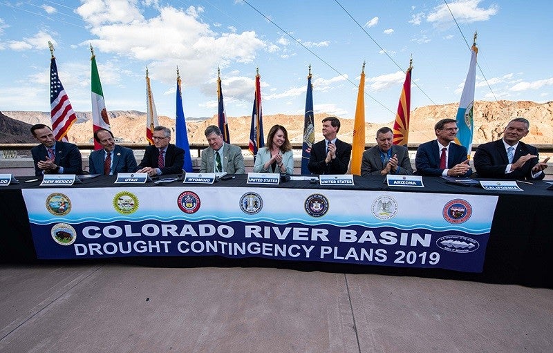 Federal and state officials sit at a table to celebrate the signing of the Colorado River drought contingency plan atop the Hoover Dam