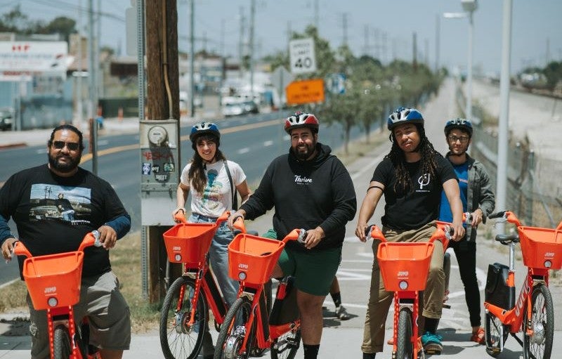 Un grupo de personas posando con bicicletas eléctricas naranjas