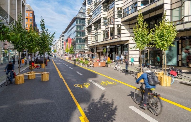 Credit: IGphotography via iStock/Getty Images Plus A bicyclist and trees on a city street