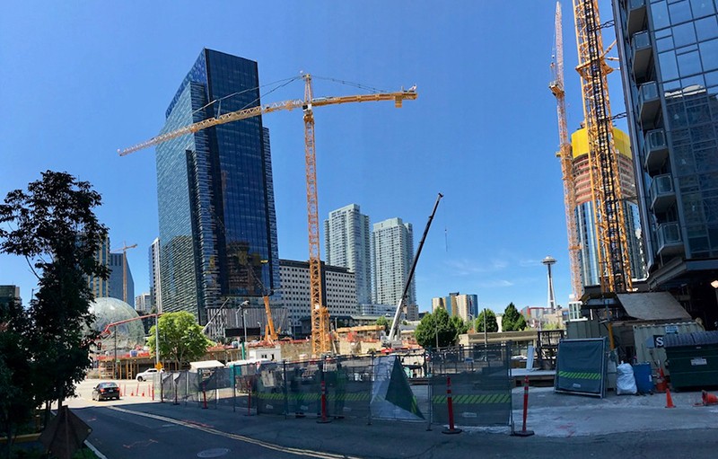 Two skyscrapers stands in front of a background of blue sky, with a crane in between.