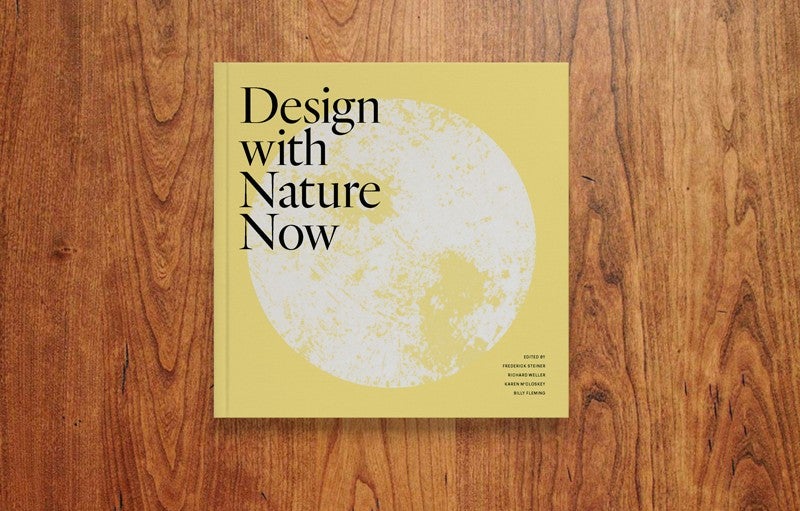 Portada de Design with Nature Now. Crédito: Julie Pizzo / Page Un libro se muestra desde arriba, acostado sobre una mesa de madera. El libro es de color amarillo pálido con un tipo negro que dice "Diseña con la naturaleza ahora" y también muestra una imagen blanca en forma de luna que ocupa la mayor parte de la portada.