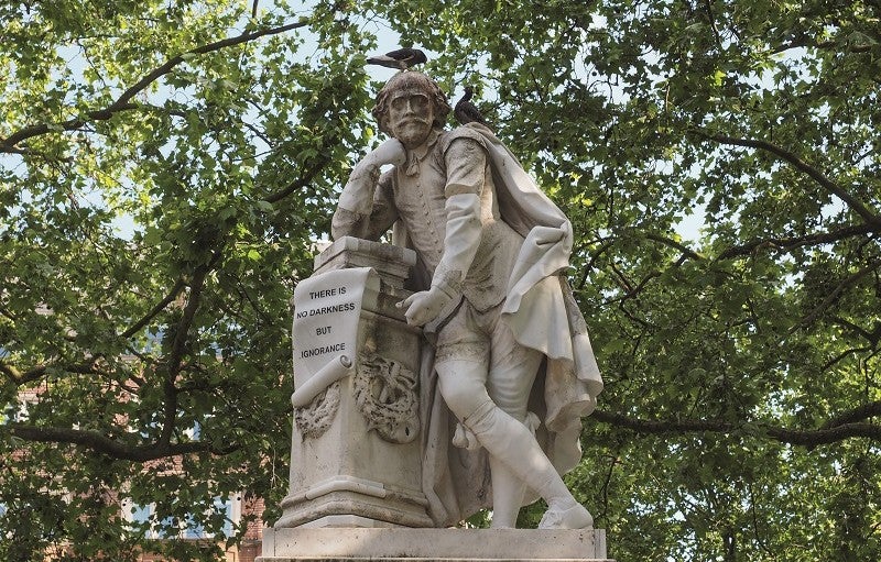 Crédito: claudiodivizia vía iStock/Getty Images Plus. Estatua de Shakespeare con árboles de fondo