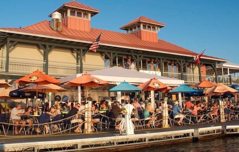 Photo courtesy of Splash at the Boathouse, Burlington Vermont A waterfront restaurant with an outdoor patio full of diners.