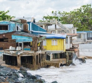 The west coast town of Rincón sustained heavy damage in Hurricane Maria. Credit: cestes001 (iStock/Getty Images Plus) Photograph shows small turquoise, yellow, and white buildings situated directly over water on a coastline in Rincón, Puerto Rico. Rough waters are visible. Rincón sustained heavy damage in Hurricane Maria. Credit: cestes001 (iStock/Getty Images Plus)