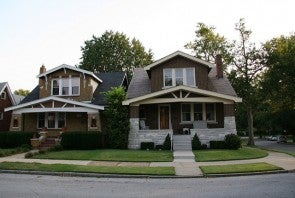 Two houses stand side by side with green lawns in the foreground.