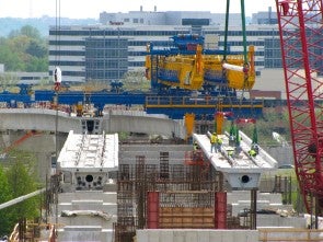 A train viaduct is under construction above a highway.