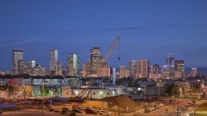 Nighttime with a train station in the foreground and tall buildings plus a crane in the background.