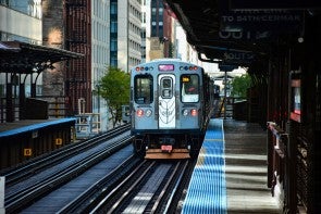 A train on a platform with buildings in the background.