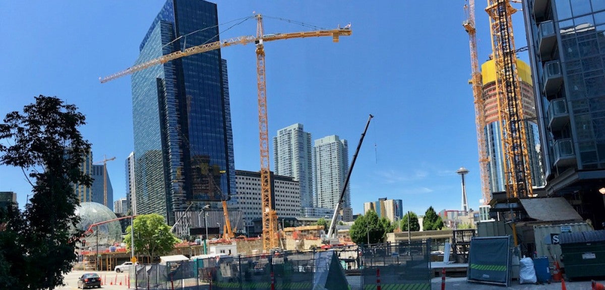 Amazon headquarters in Seattle Two skyscrapers stands in front of a background of blue sky, with a crane in between.