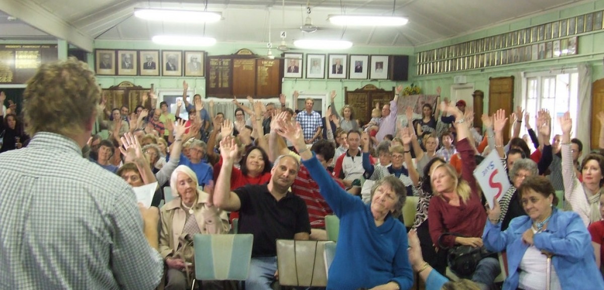 People in a meeting in a classroom with hands raised