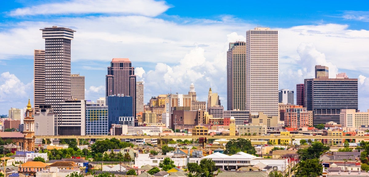 A cit skyline with large buildings in the background and smaller buildings and trees in the foreground. It's daytime.